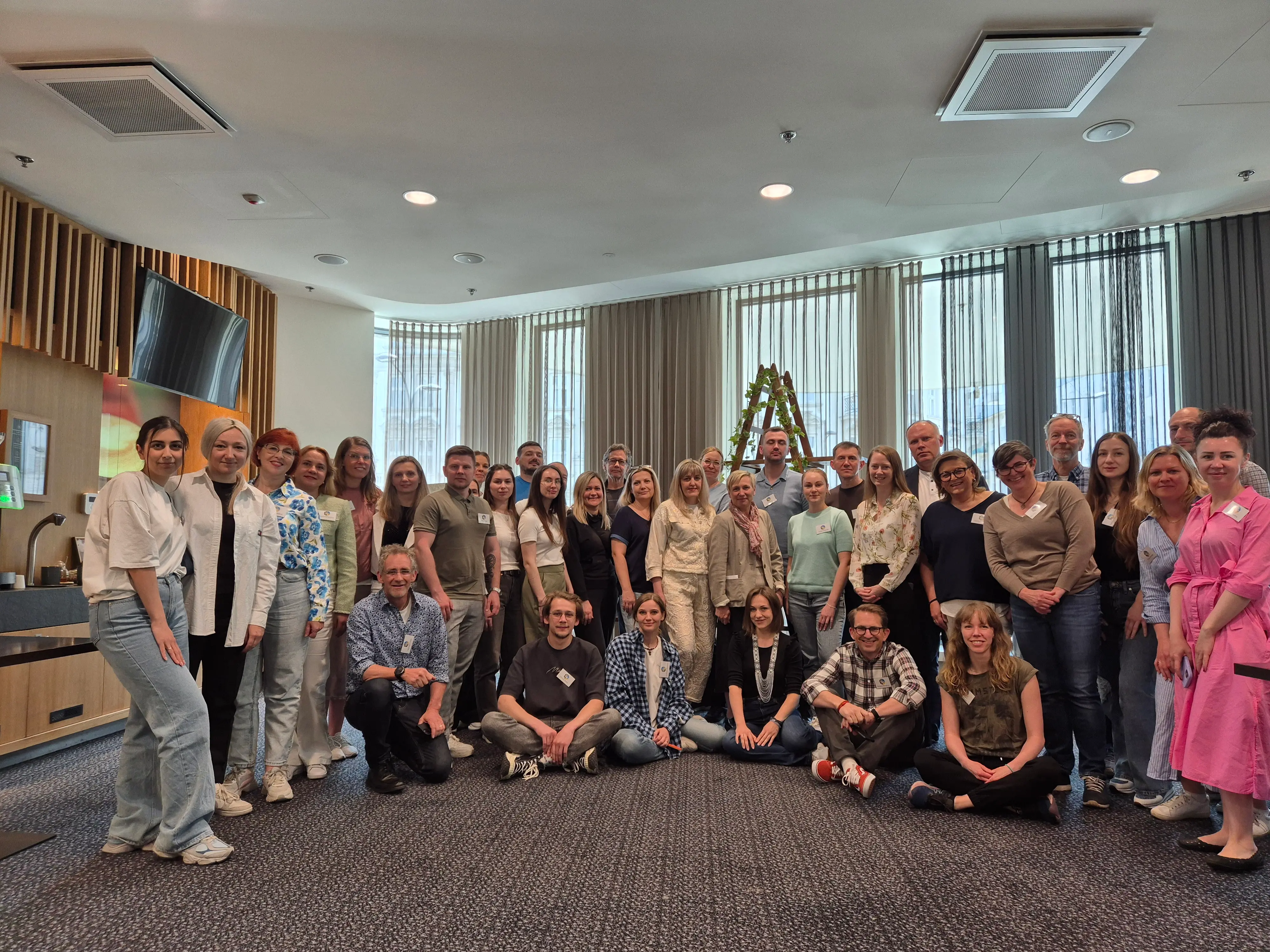 En stor grupp människor ler och tittar in mot kameran