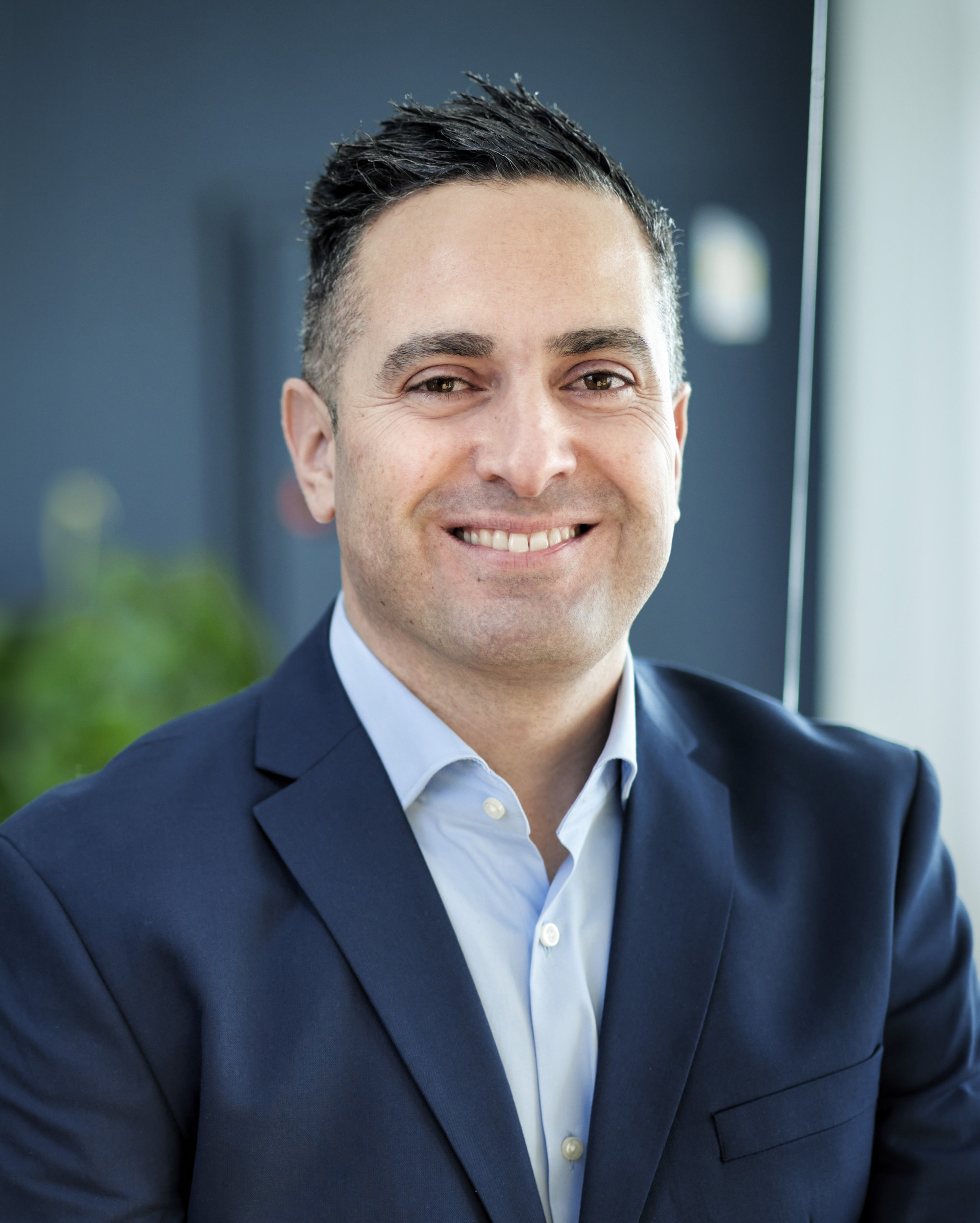 En man i kostym som ler mot kameran.