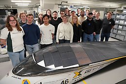 Students and teacher behind a solar car.